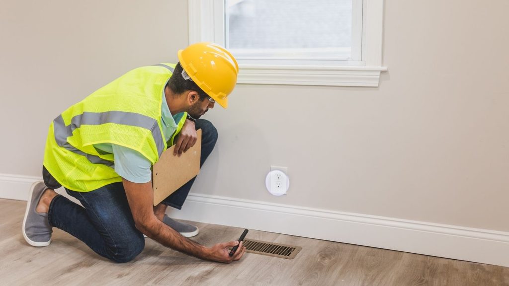 Home inspector examining a floor vent during a residential home inspection.