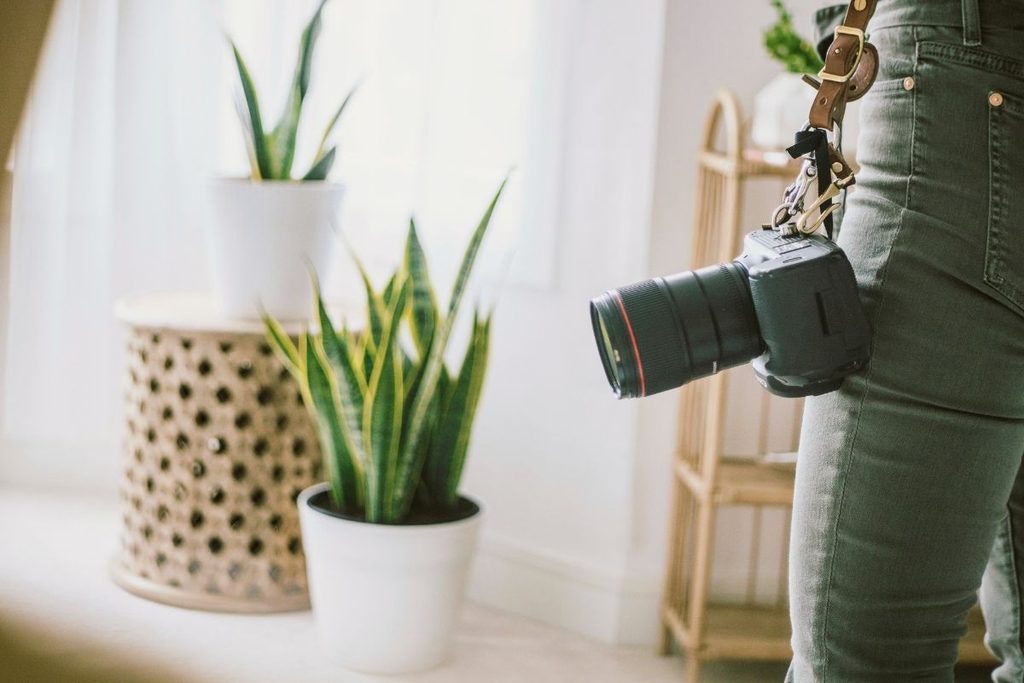 Real estate photographer with a professional camera inside a prepared home.