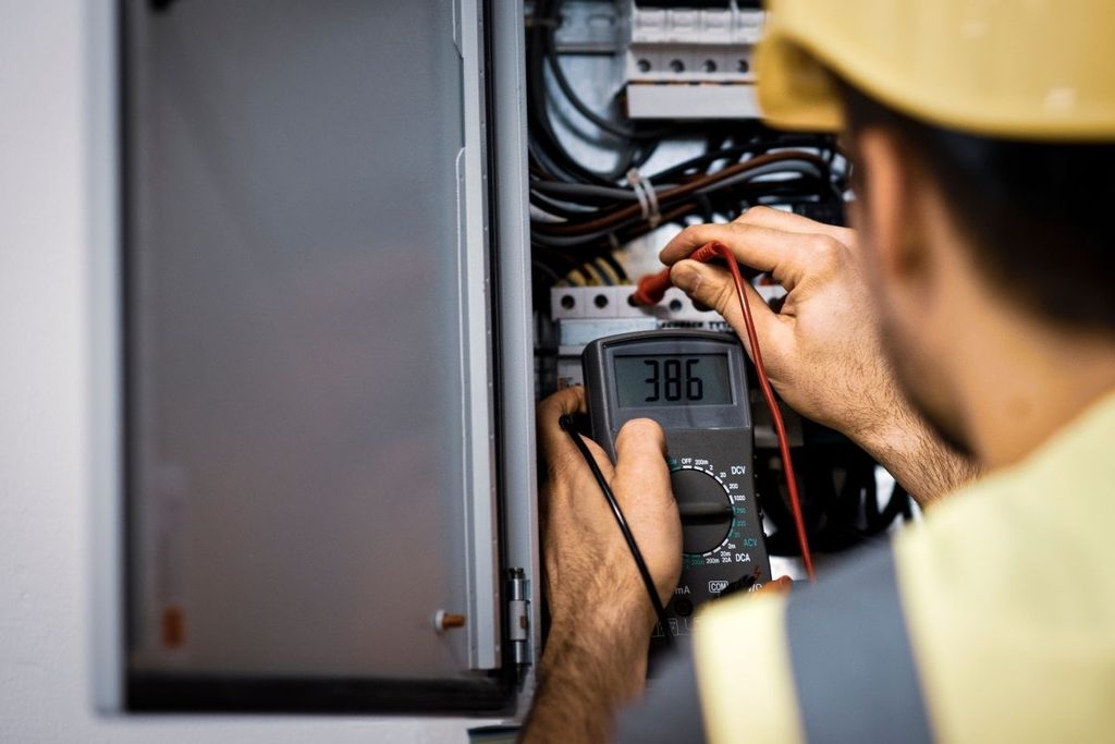 Electrical panel being tested with a multimeter during a home inspection.