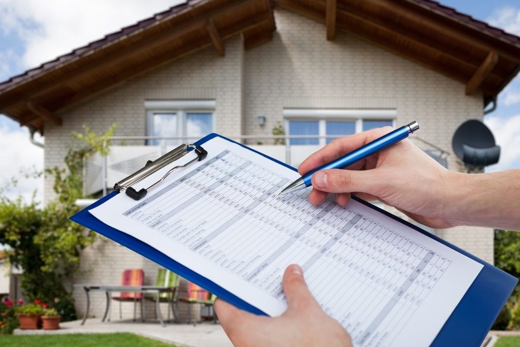 Inspector reviewing a residential home inspection report on a clipboard.