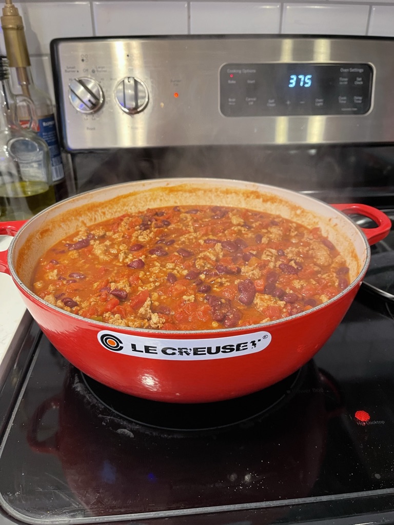 Ground turkey chili simmering in a red Le Creuset pot on the stovetop
