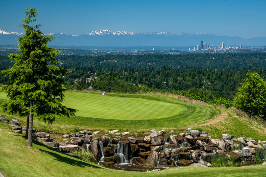 Putting green with a waterfall at The Golf Club at Newcastle, with the Seattle skyline and mountains beyond
